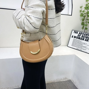 Detail of khaki crescent saddle bag with golden metal hardware and adjustable strap