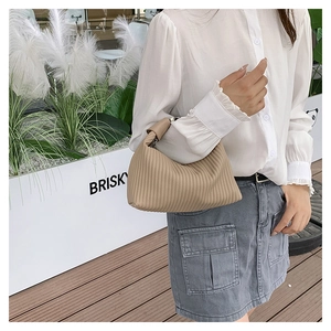 Detail of khaki pleated dumpling bag with vertical texture and seamless handle