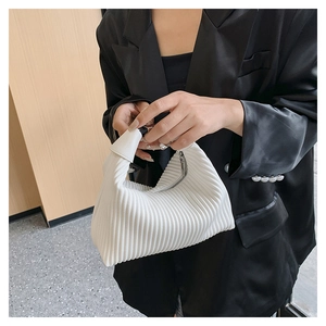 Close-up of white pleated handbag with vertical texture and silver zipper detail