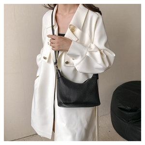 Detail of black pleated crescent bag featuring vertical organza style textures and fine strap