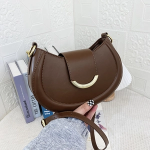 Close-up of brown leather crescent bag with golden buckle and adjustable strap