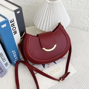 Macro shot of burgundy saddle bag showing smooth texture and golden crescent buckle