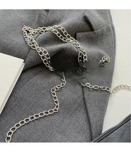 Detail of a shiny silver chain strap on a grey blazer for a modern aesthetic look