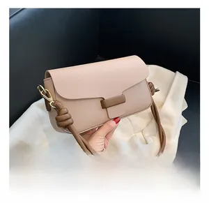 Detailed macro view of the lychee grain texture and brown strap on a beige crossbody bag
