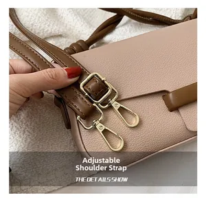 Detail shot of beige pebble leather handbag with brown adjustable strap and gold metal hardware