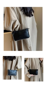 Detail of black leather pillow bag with pearl trim and metal chain strap decoration
