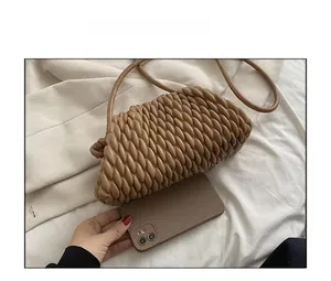 Brown woven crossbody handbag size comparison with smartphone on beige fabric