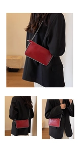 Detail of red leather crossbody pillow bag with silver bead trim and metal chain strap