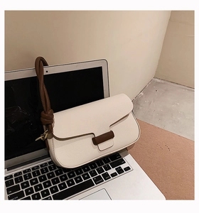Detail of off-white lychee texture leather handbag with brown knotted strap and gold hardware