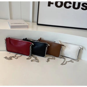 Detailed view of four elegant crossbody bags with pearl trim in red, black, brown, and white