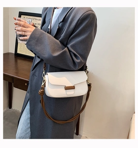 Detail of white pebbled leather crossbody bag with brown strap on a stylish model