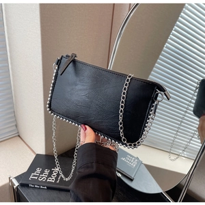 Detail of black faux leather pillow bag featuring silver beaded edges and chain strap
