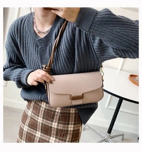 Detail of minimalist shoulder bag in pink and brown with leather strap and metal hooks