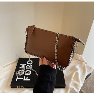 Detail of brown litchi pattern leather bag with silver bead trim and metal chain strap