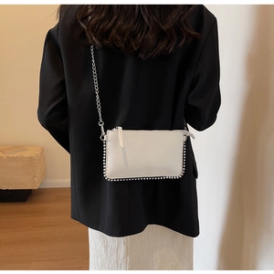 Detail of white rectangle crossbody bag with silver bead trim and detachable chain strap
