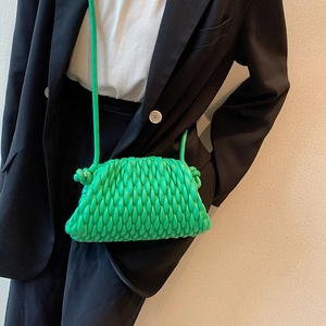 Detail view of a bright green pleated cloud bag styled with a black blazer for a chic look