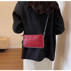 Macro shot of red faux leather mini bag with silver stud trim and chain strap