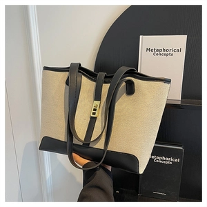 Detail of canvas tote bag with black leather trim and golden metal lock clasp