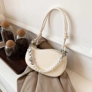 Chic cream crescent shoulder bag with pearl heart chain over a khaki blazer coat
