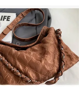 Vista dettagliata della borsa trapuntata marrone con catena su un blazer grigio