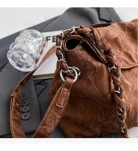 Dettaglio borsa in pelle trapuntata marrone scuro con catena argento e texture vintage