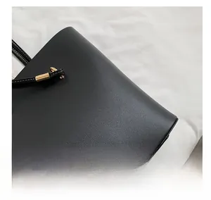 Close-up of black leather tote bag featuring fine stitching and gold metal buckles