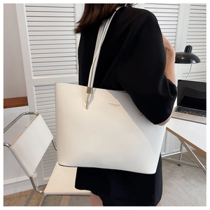 Detail of the white matte leather tote bag featuring gold lettering and metal hardware