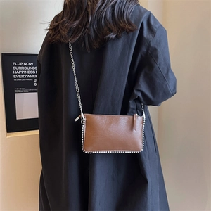 Brown leather pillow bag with silver bead trim and a sleek chain strap for women