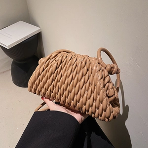Elegant camel woven dumpling handbag with pleated leather texture held by a model