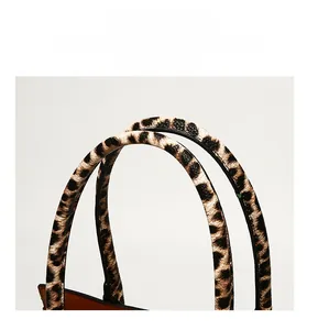 Détail des poignées de sac à main à motif léopard avec bordures noires et surpiqûres