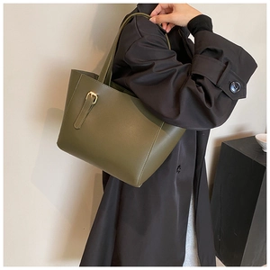 Détail du cabas en similicuir vert foncé avec boucle dorée sur un manteau noir