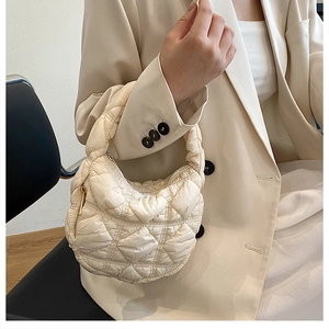 Detailed view of cream-colored quilted puffer shoulder bag with elegant pleated texture