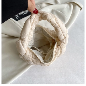 Detail of beige puffer bag showing interior compartment with zipper and quilted texture