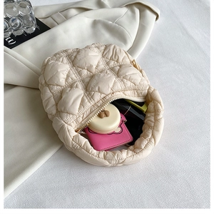 Detail view of a beige quilted puffer handbag with textured fabric and zipper closure
