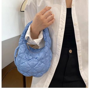 Detail of light blue quilted puffer handbag with textured nylon fabric and zipper