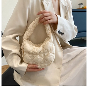 Detail of a beige quilted hobo bag featuring soft pleated design and zipper closure