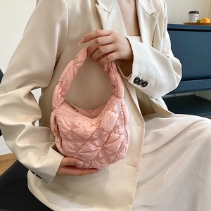Pink quilted cloud handbag with wavy pleats and gold zipper carried by a model