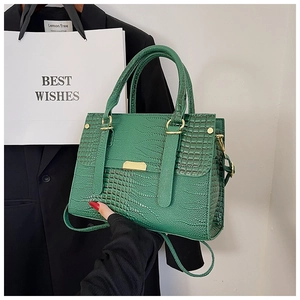 Detail of green crocodile texture handbag with golden hardware on a black suit background