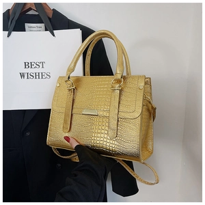Detail shot of golden crocodile pattern texture and metallic clasp on the stylish handbag
