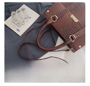 Detail of dark brown crocodile embossed crossbody bag with gold metal rings and studs