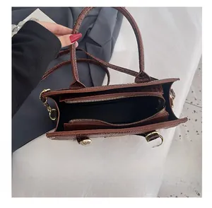 Detail view of the deep brown crocodile embossed handbag interior with golden zipper