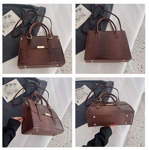 Detail view of brown crocodile texture tote bag with gold hardware and bottom rivets