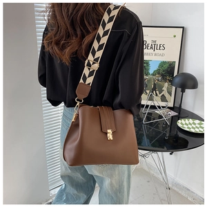 Detail of vintage brown leather bag with golden hardware and herringbone woven strap