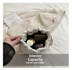 Interior capacity of white cloud bucket bag showing phone and cosmetics with gold chain