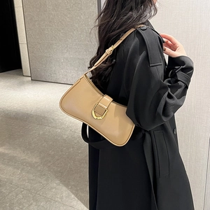 Detail of khaki shoulder bag with gold horsebit buckle styled on a black trench coat