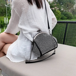 Outdoor shot of a black rhinestone kiss-lock bag with dual leather and chain straps