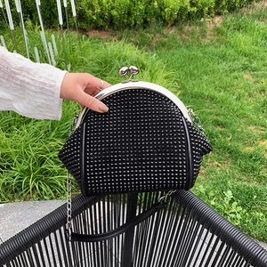 Close-up of black rhinestone evening clutch with silver kiss-lock and metal chain strap