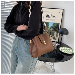 Brown leather trapezoid shoulder bag with geometric woven strap and gold metal clasp
