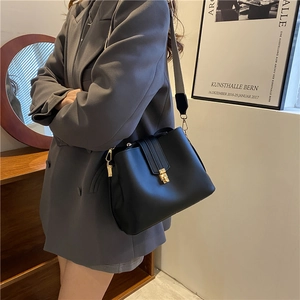 Black minimalist bucket bag with gold buckle and wide adjustable fabric shoulder strap