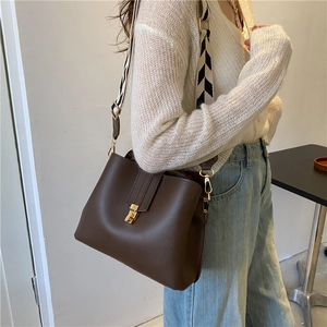 Dark brown leather bucket bag with golden buckle and geometric patterned wide strap